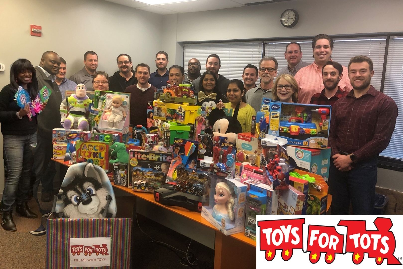 Satuit Technologies employees standing in conference room filled with toys for toys for tots