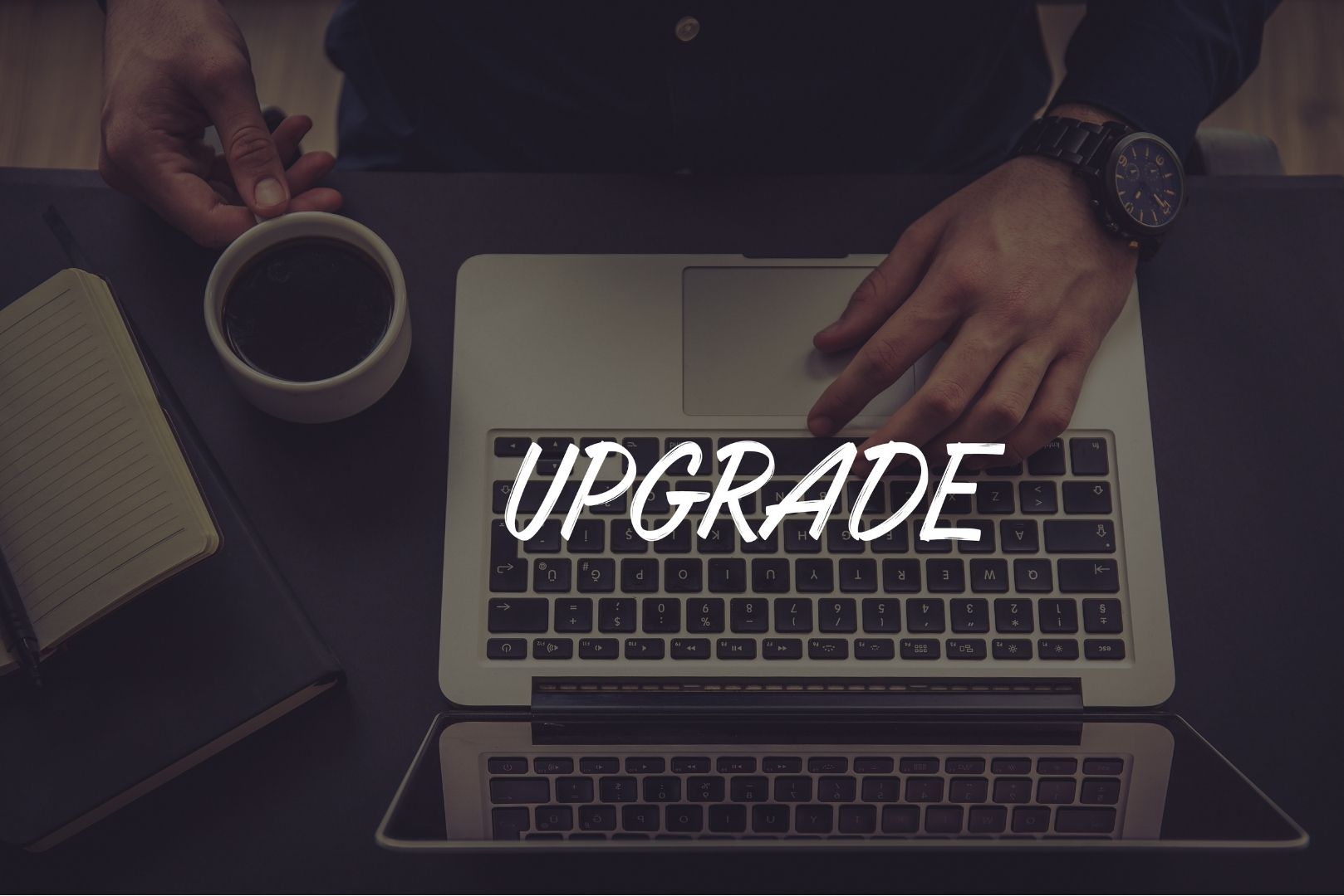 bird's eye view of man typing on mac with the word "Upgrade" overlaying the image