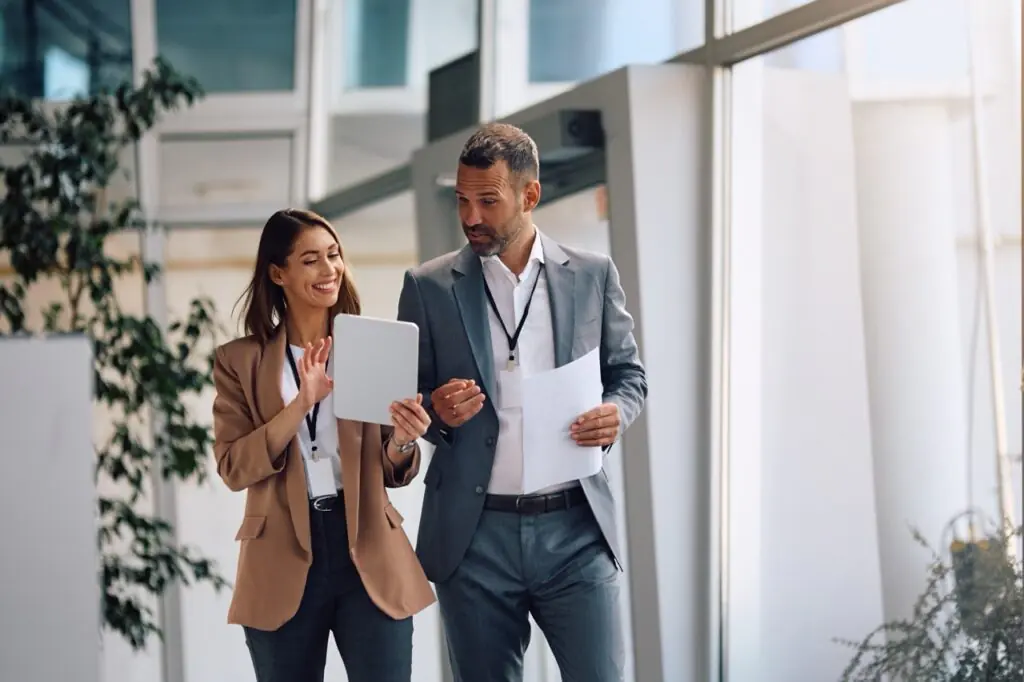 Businesswoman and colleagues reviewing a SatuitCRM vs Freshsales comparison on a tablet
