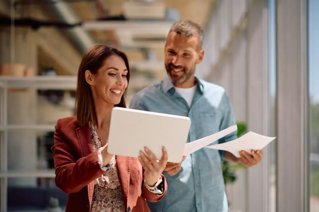 Businesswoman and colleague reviewing SatuitCRM workflow automation on a tablet