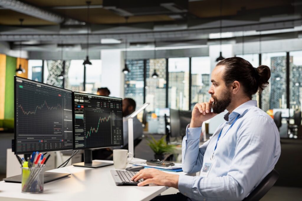 Investment professional analyzing data at multiple monitors while comparing SatuitCRM vs Attio