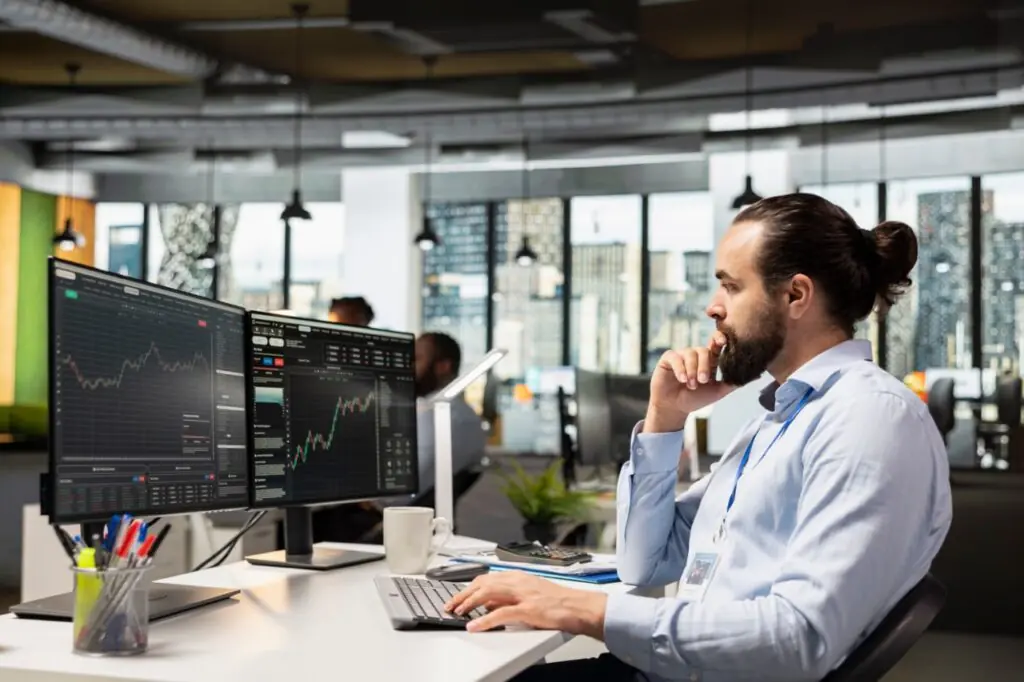 Investment professional analyzing data at multiple monitors while comparing SatuitCRM vs Attio